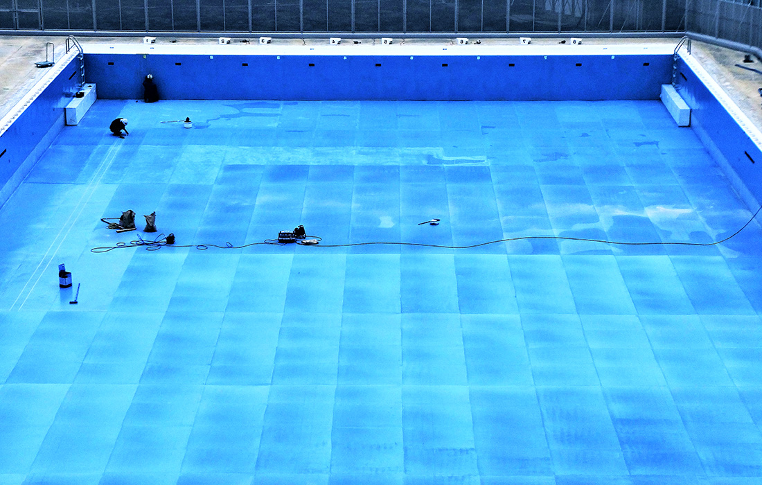 プールに瞬間硬化型ポリウレア樹脂で防水を施している様子